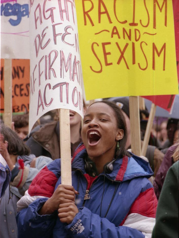A person holds a sign that reads "Fight, Defend Affirmative Action" at a demonstration.