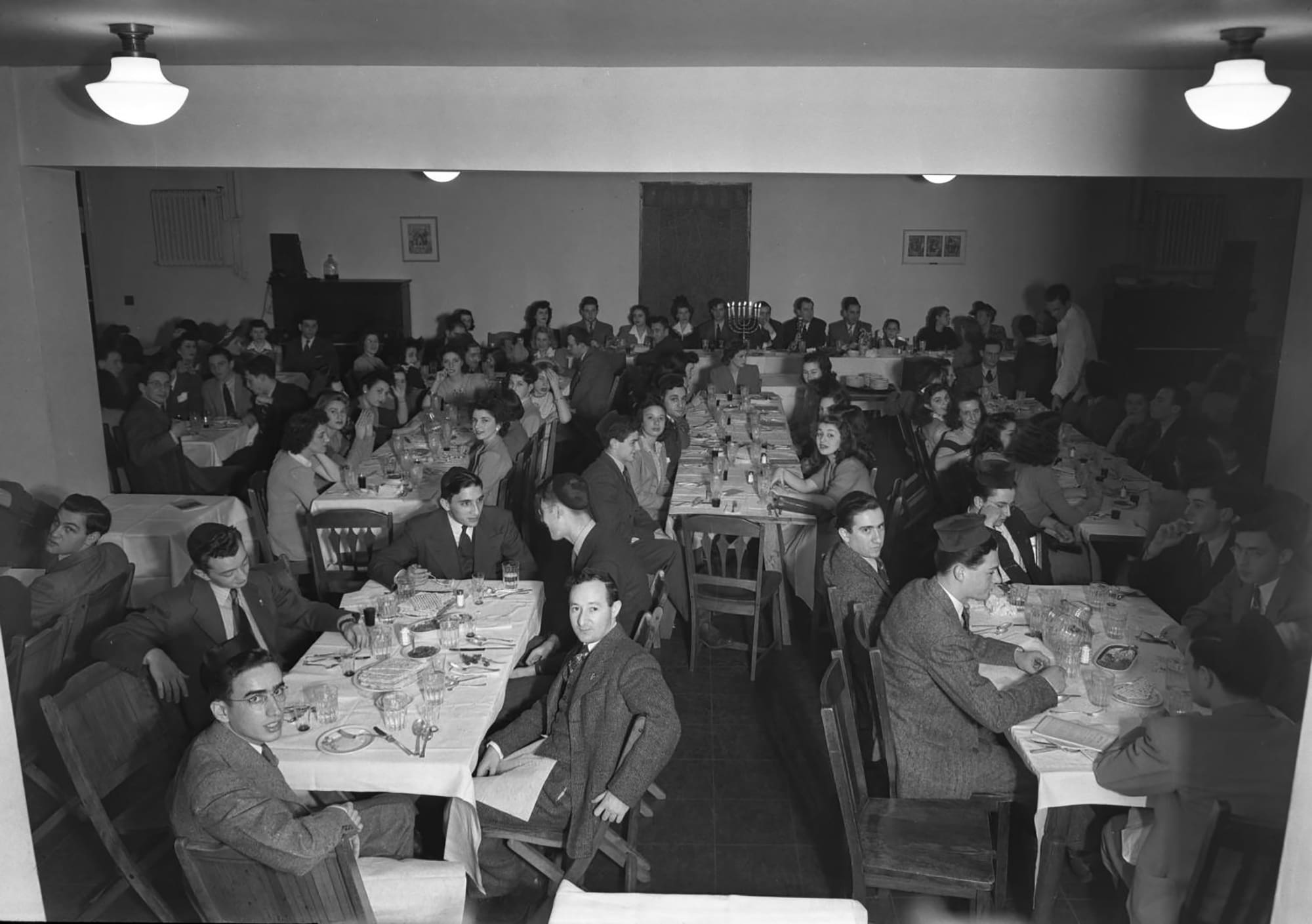 People gather around tables for Passover seder.