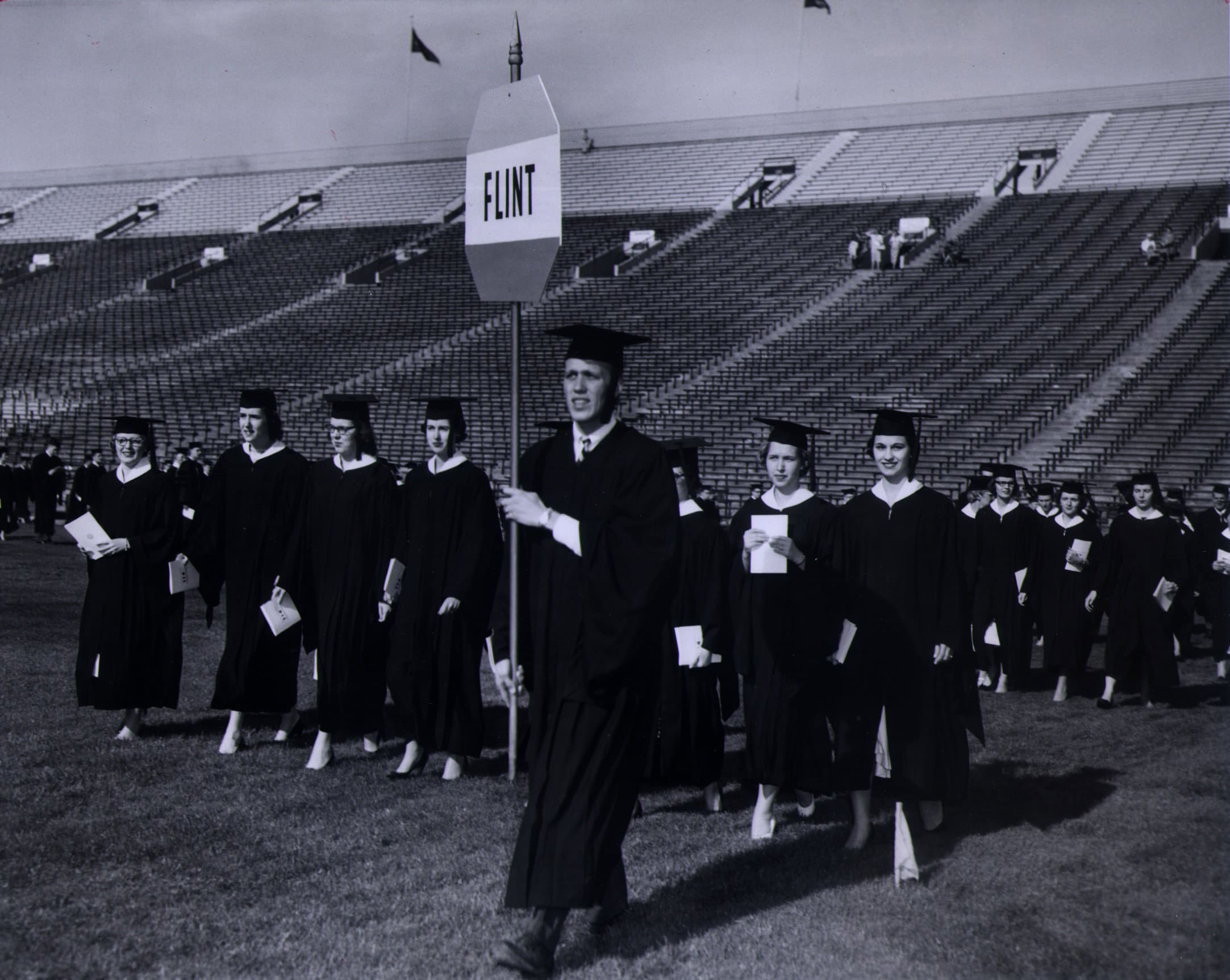 Flint graduates walk across the Michigan Stadium field in Ann Arbor.