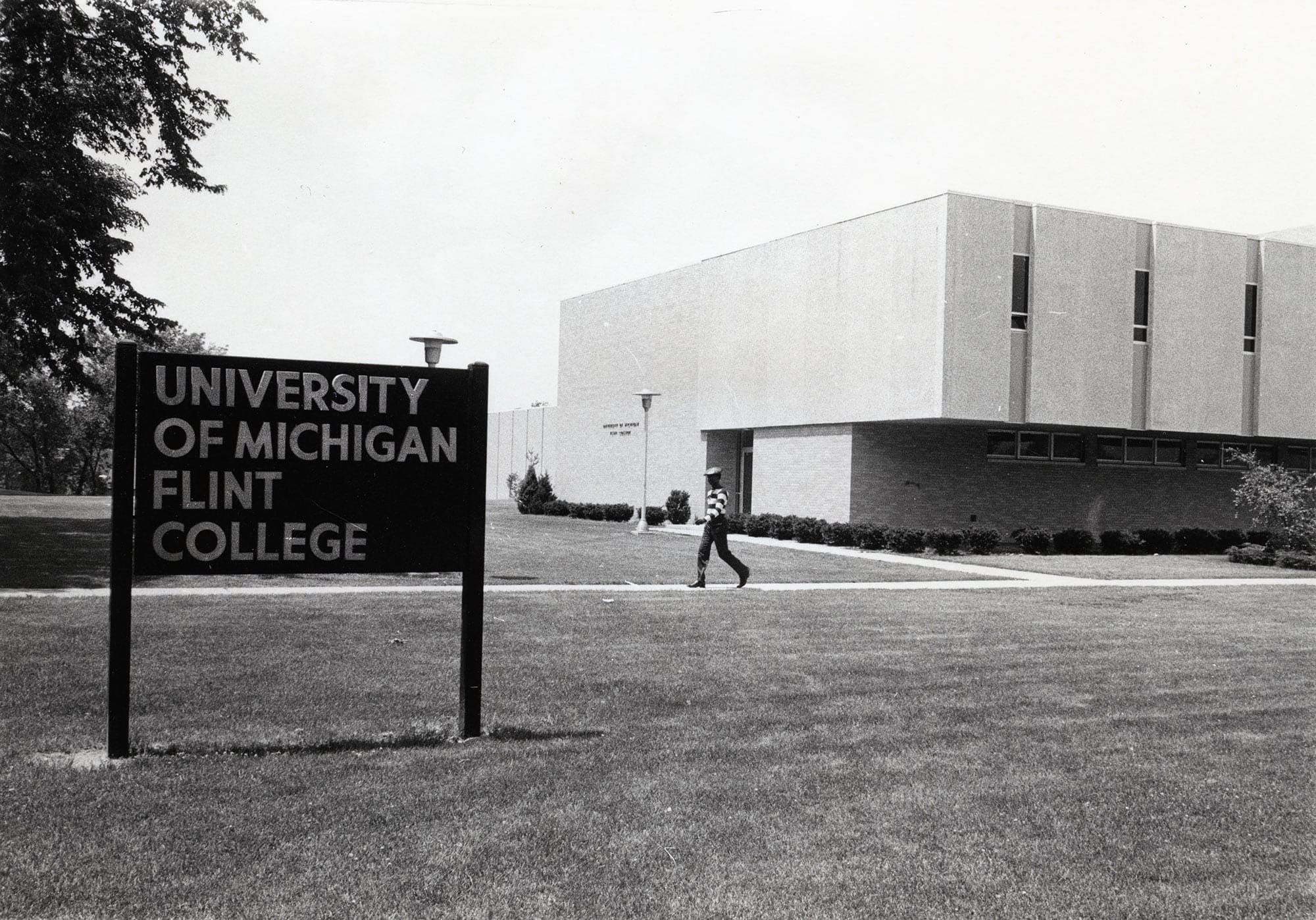 Young man walking outside U-M Flint College, 1970