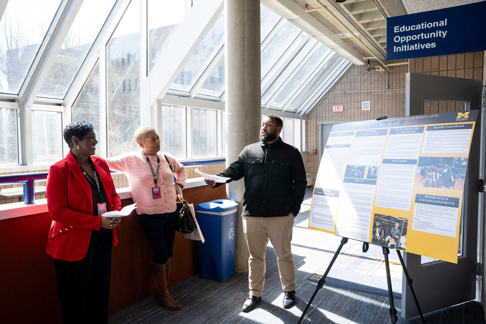 3 people stand beside a research poster outside the Office of Educational Opportunity Initiatives
