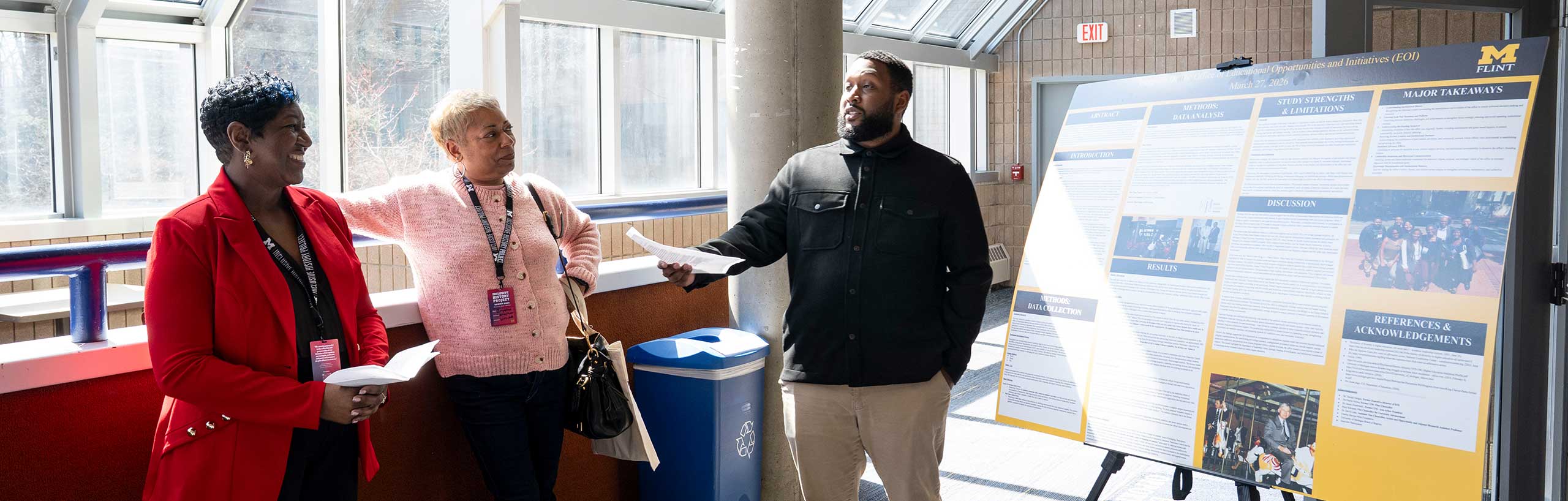 3 people stand beside a research poster outside the Office of Educational Opportunity Initiatives