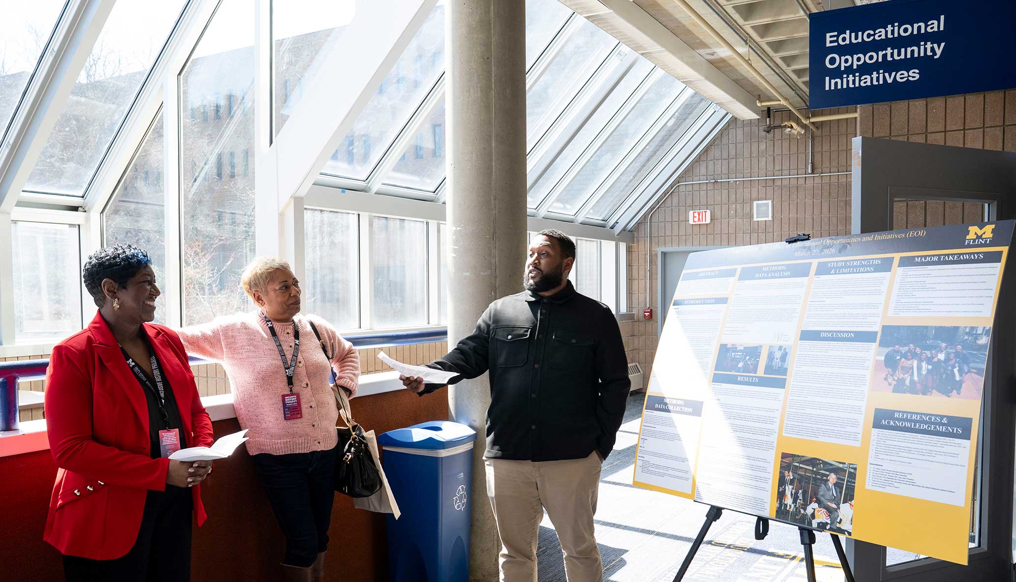3 people stand beside a research poster outside the Office of Educational Opportunity Initiatives