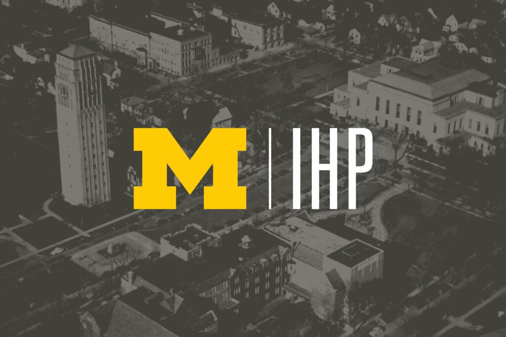 alt=”The U-M and IHP logos centered over a dark grayscale aerial image of a city.”