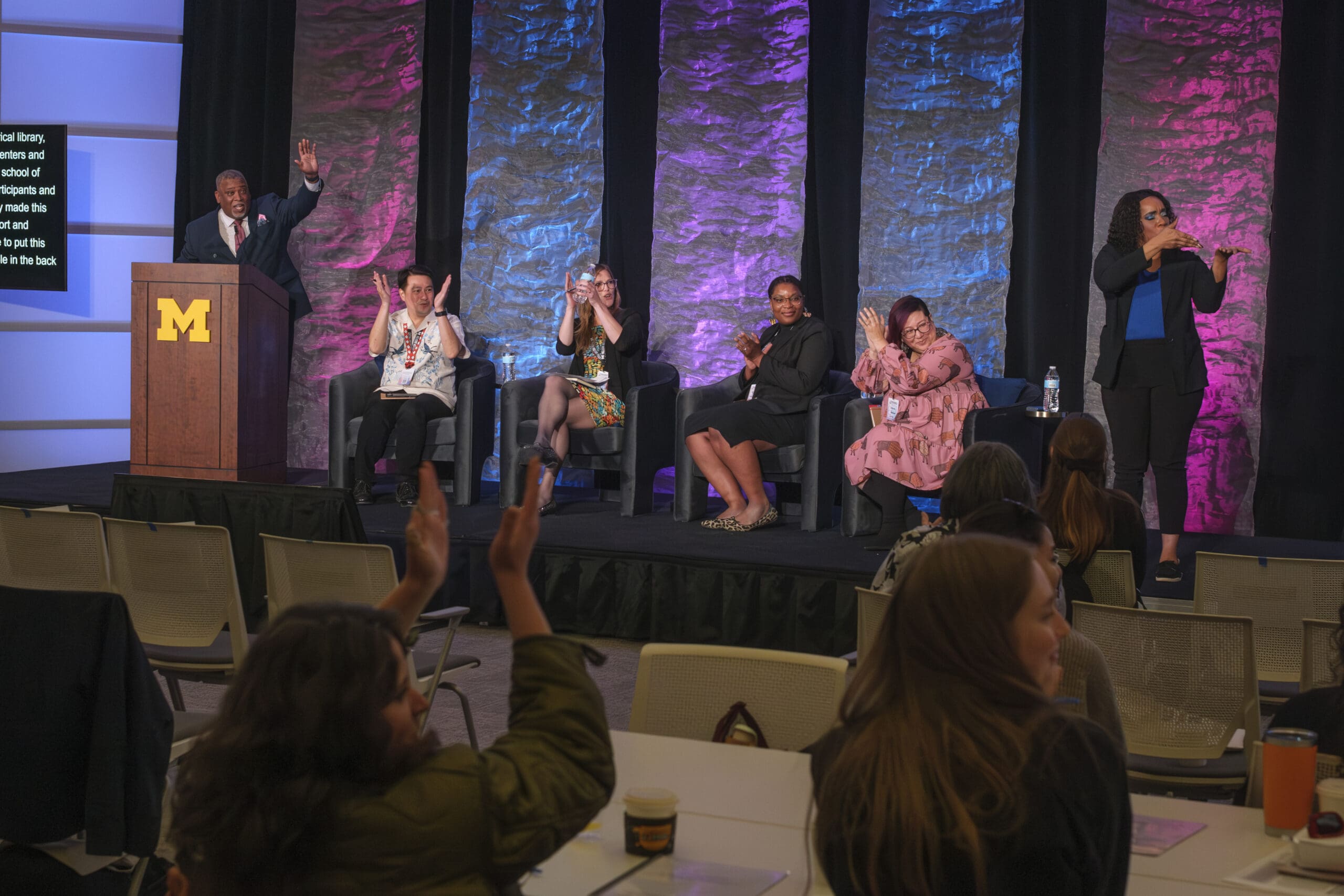 Panelists clapping at the Communities in Conversation Symposium.