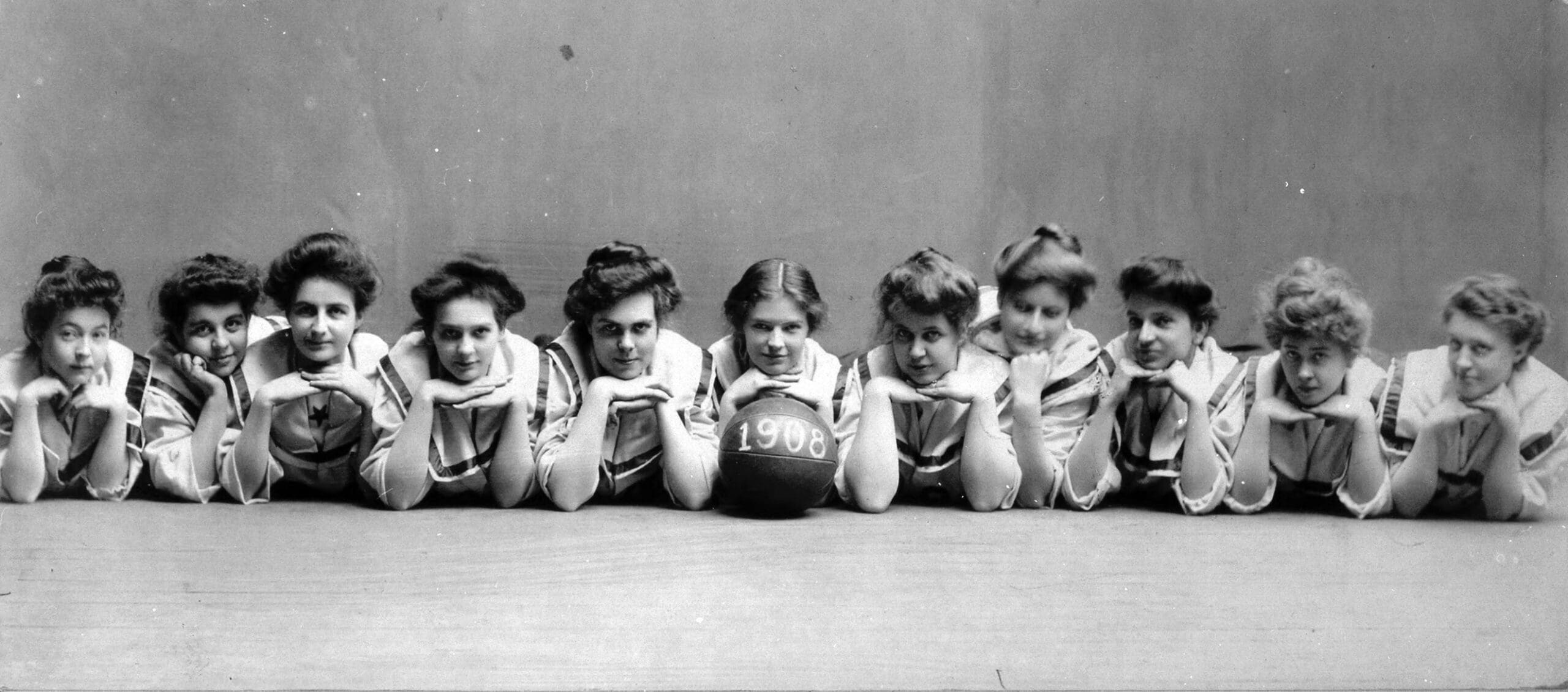 Group of women laying on their stomachs, propping their chins up on their hands.