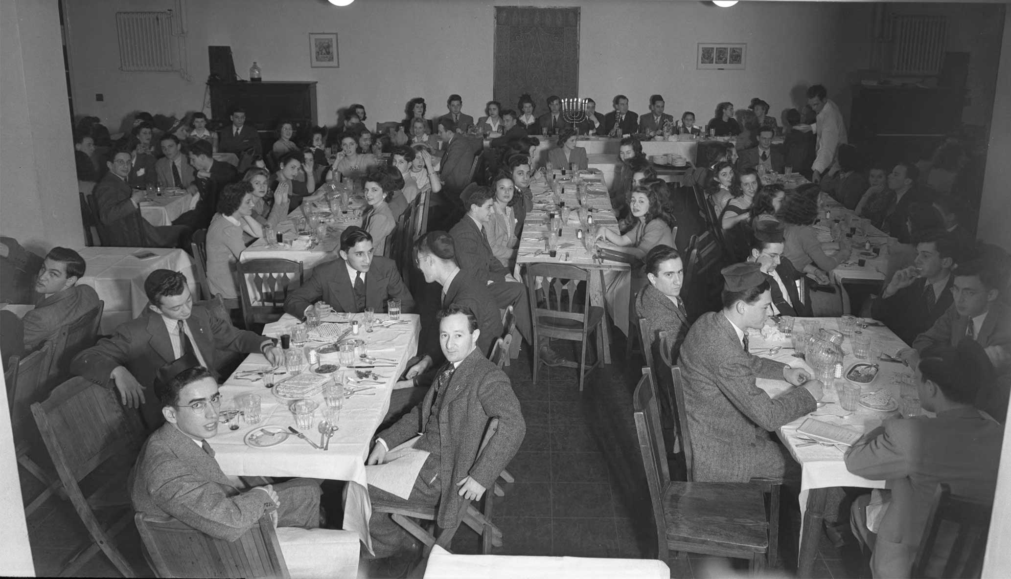 People gather around tables for Passover seder.