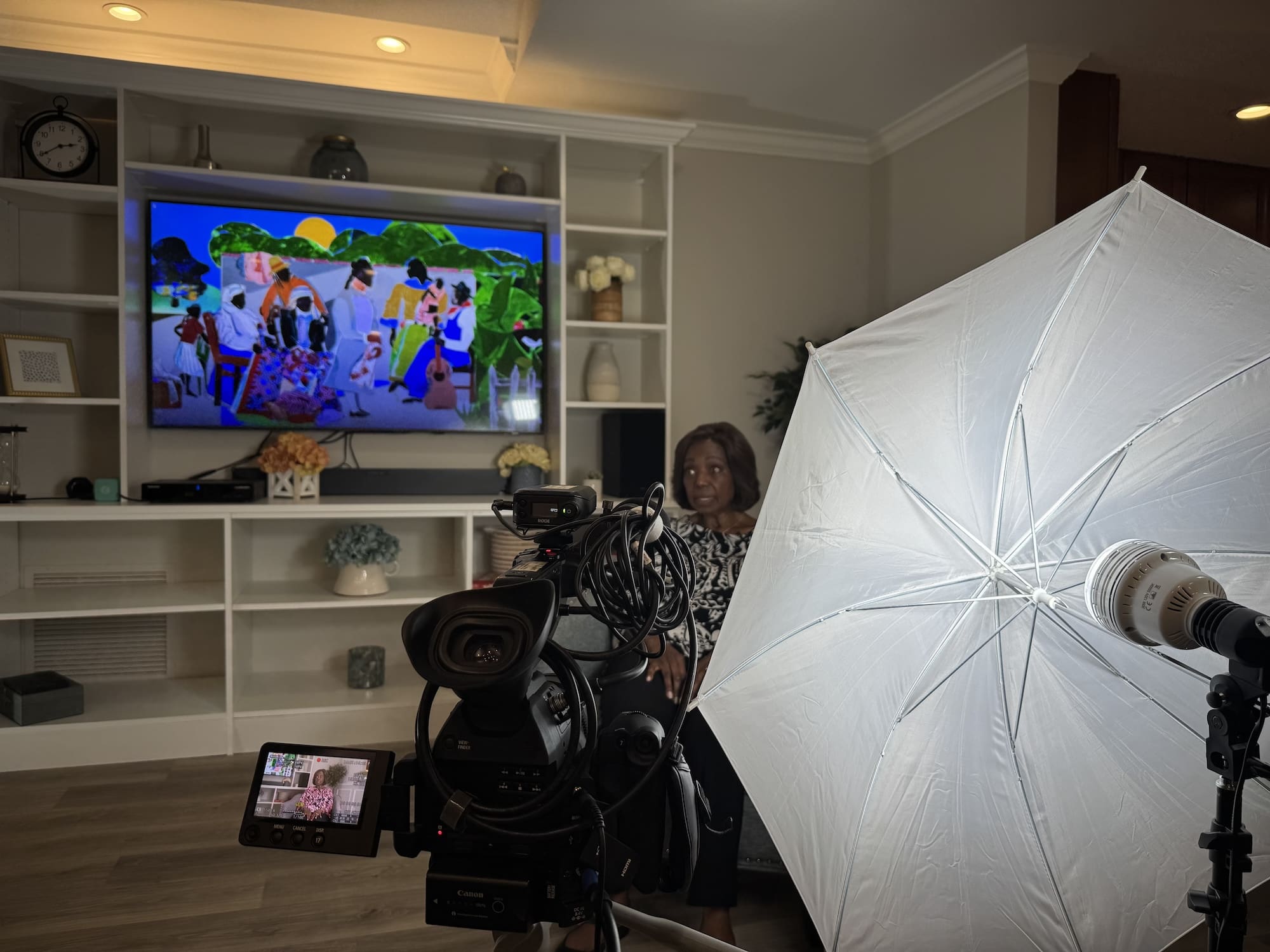 A camera and umbrella light turned taping the interivew Blenda Wilson, who sits in front of a bookshelf.