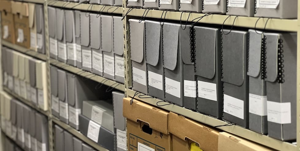 Archival boxes on shelves in the Dearborn Campus Archive.