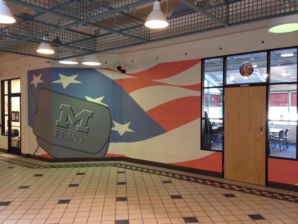 Entrance to UM-Flint's Student Veterans Resource Center (SVRC) which features a mural of the UM-Flint logo on military identification tags with the stars and strips motif of the United States flag in the mural's background.