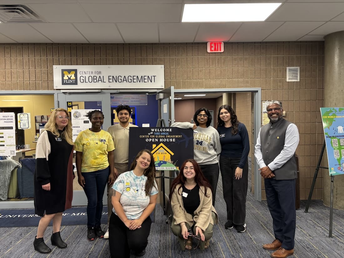 Group of staff members standing in front of the Center for Global Engagement office door at UM-Flint.
