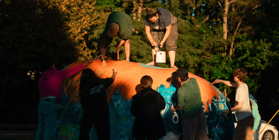 People painting a large rock
