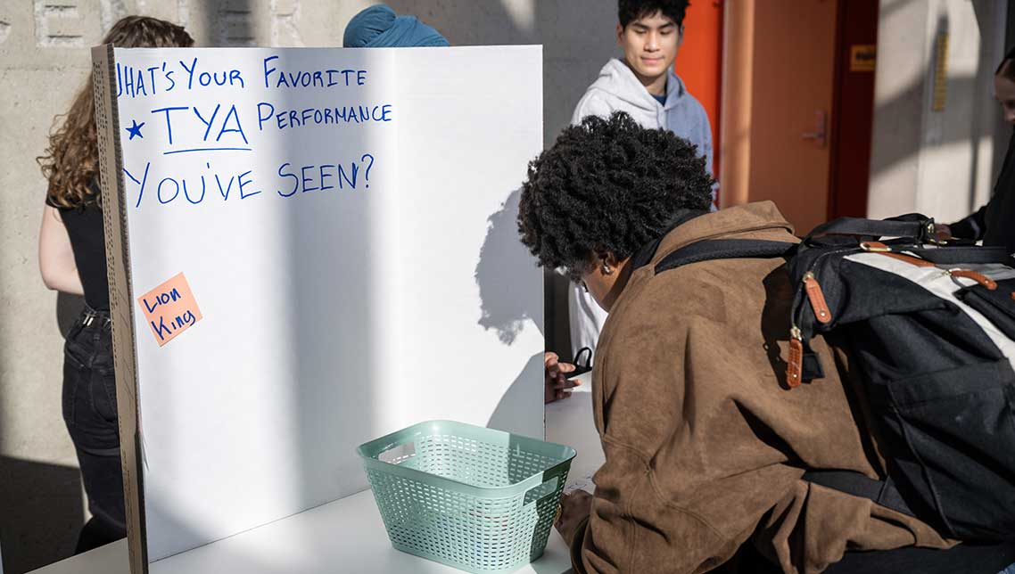 A passerby engages with student projects in the lobby of the Walgreen Drama Center.