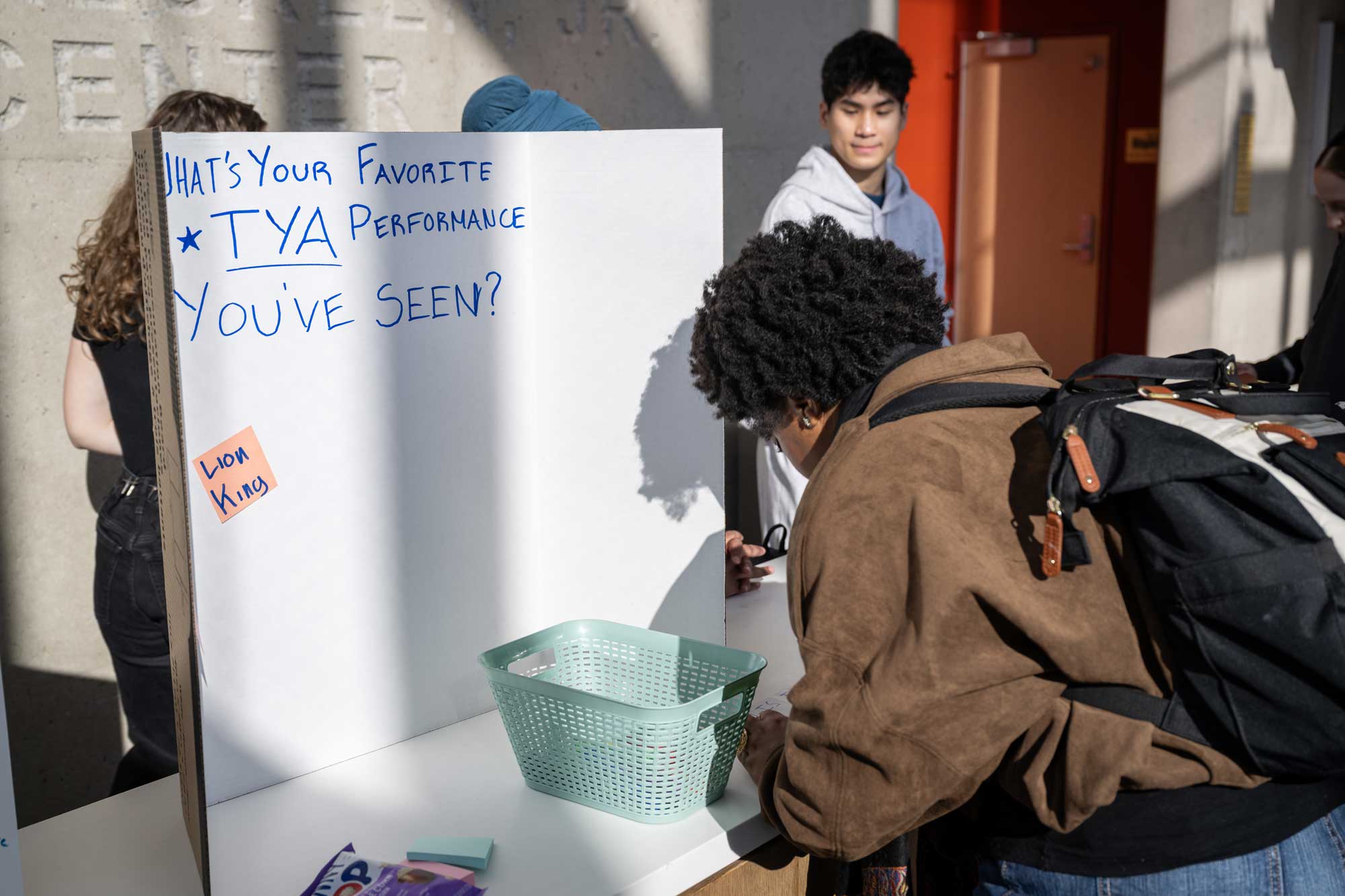 A passerby engages with student projects in the lobby of the Walgreen Drama Center.