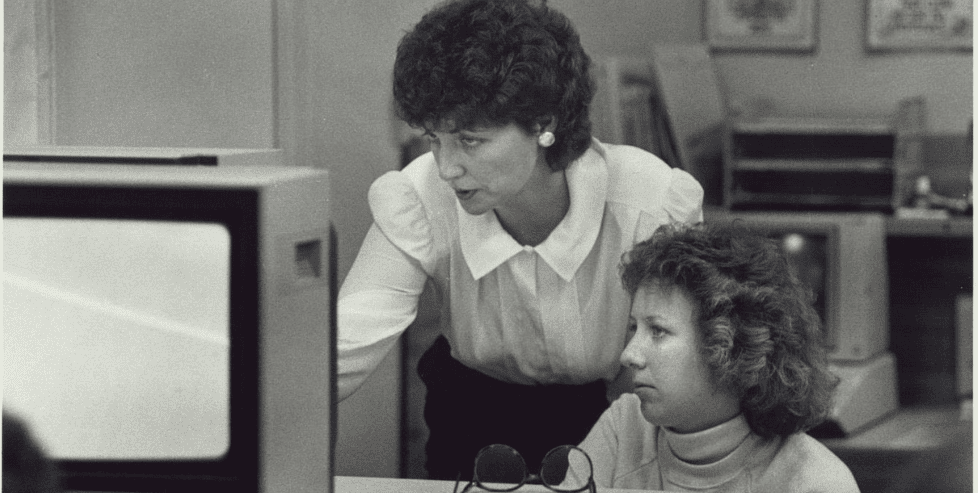 Black-and-white photo of two women looking at a computer.