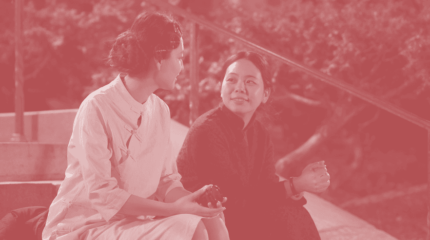 Two women sitting and smiling at each other.